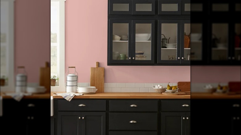 Cocina con paredes rosas y gabinetes oscuros.