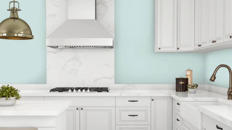 Cocina con encimeras de mármol blanco, gabinetes blancos y paredes azules.
