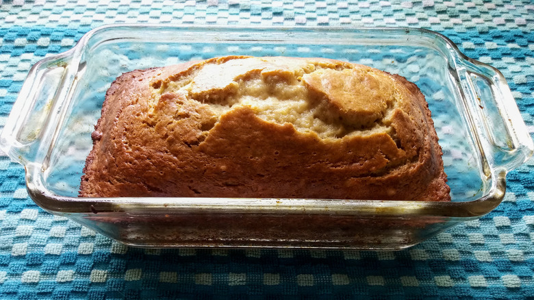 Pan de plátano en una fuente de vidrio para hornear enfriándose sobre una toalla de cocina