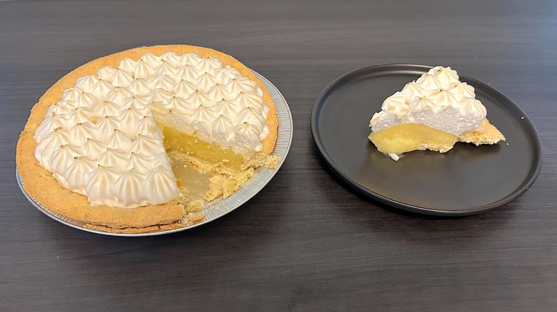 Pastel de merengue de limón de Marie Callender al que le falta una rodaja y la rodaja en un plato negro