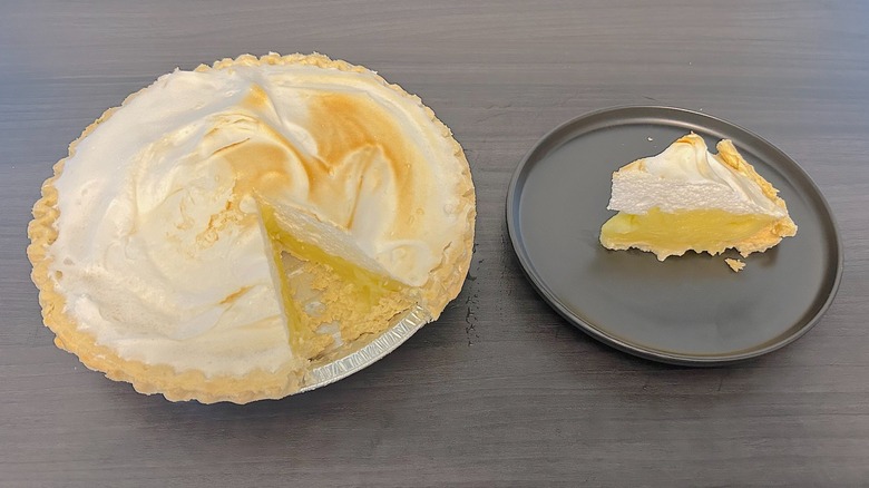 Tarta de merengue de limón Hy-Vee al que le falta una rodaja y una rodaja en un plato negro