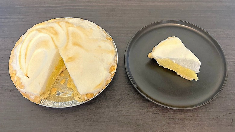 Tarta de merengue de limón sin azúcar con una rodaja extraída y la rodaja en un plato negro