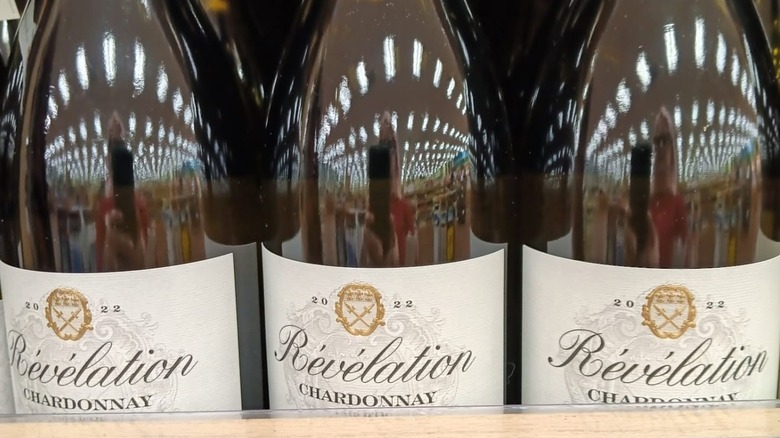 Un primer plano de tres etiquetas y botellas de Révélation Pays d'Oc Chardonnay en un estante