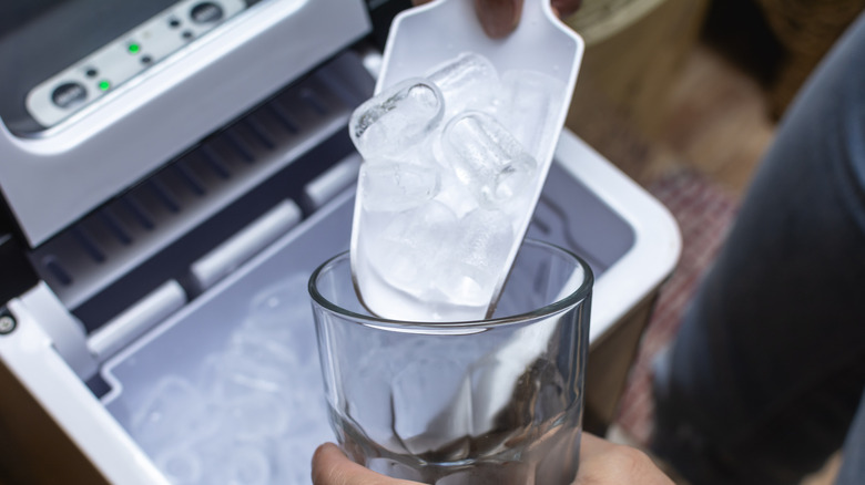 Sacar hielo de una máquina de hielo de mostrador y colocarlo en una taza