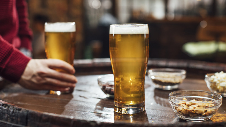 Un vaso de cerveza y un plato de maní.