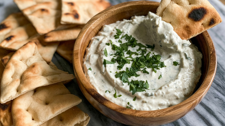 salsa de queso feta batida en un recipiente de madera con pan de pita