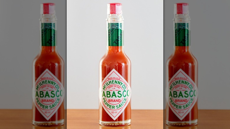Una botella de salsa tabasco roja sobre fondo gris