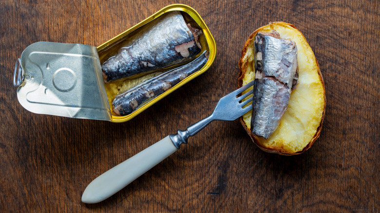 Lata de sardinas con pan con mantequilla y tenedor