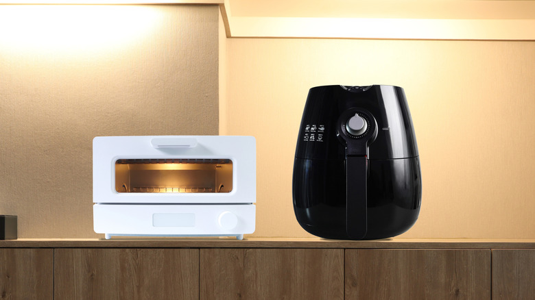 Horno tostador blanco y freidora negra uno al lado del otro en un mostrador