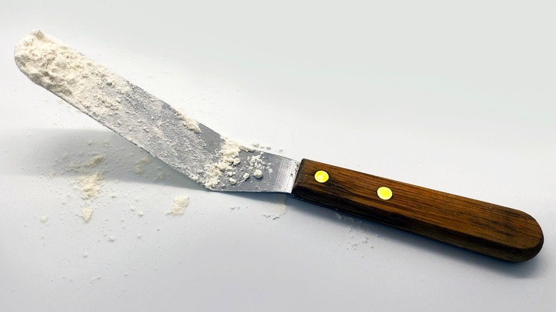 Baker untando glaseado sobre un pastel con una espátula acodada