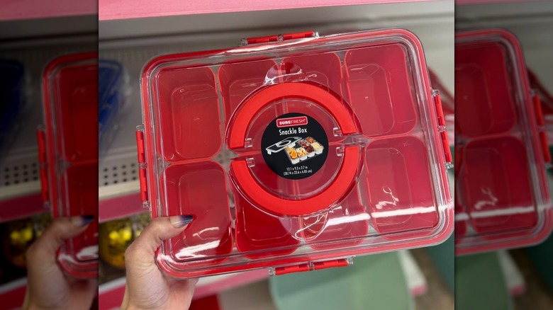 Una mano sosteniendo una caja roja de snacks SureFresh en la tienda