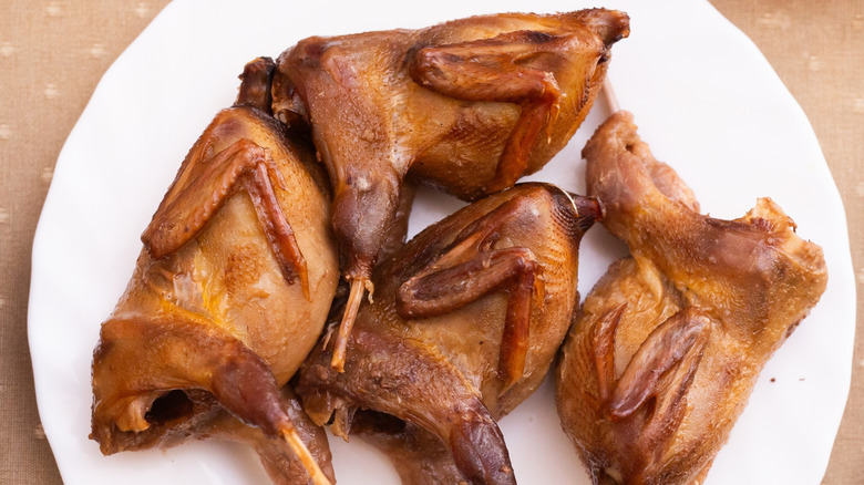 Cuatro aves de caza menor cocidas enteras en un plato blanco