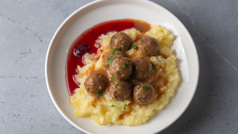 Albóndigas tradicionales suecas en un plato blanco con puré de patatas y mermelada de arándanos rojos