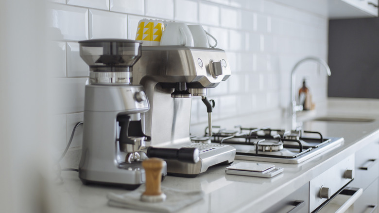 Máquina de café expreso y molinillo de café en el mostrador de la cocina casera moderna