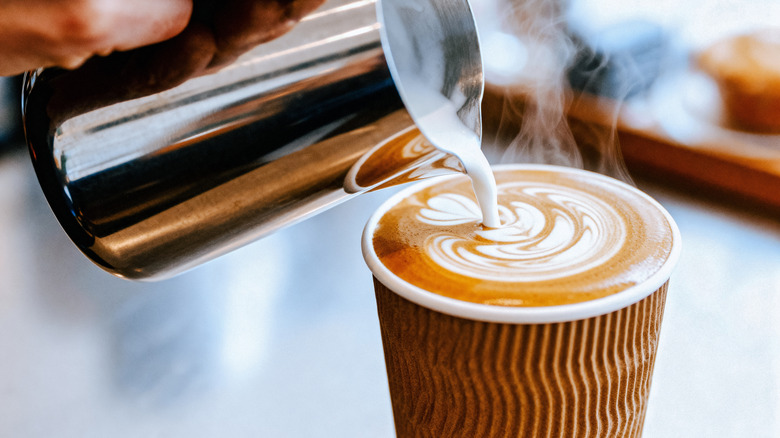 Leche al vapor vertida en un café con leche, creando arte latte