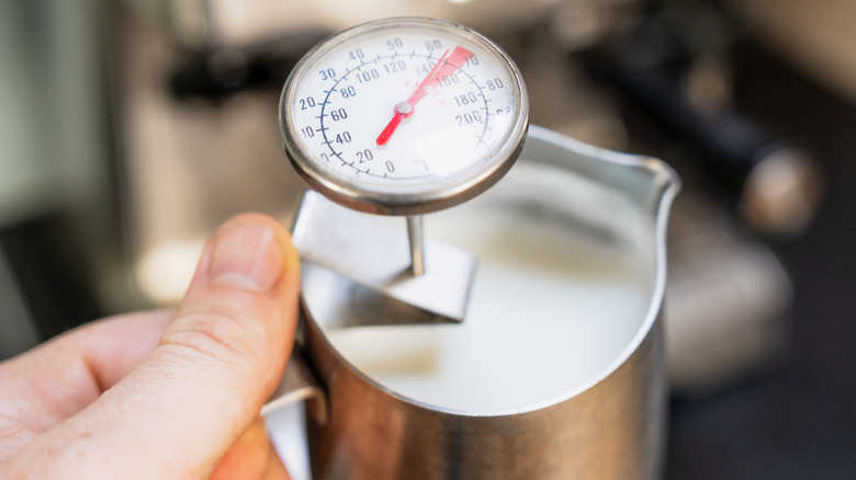 Termómetro que mide la leche al vapor en una jarra plateada