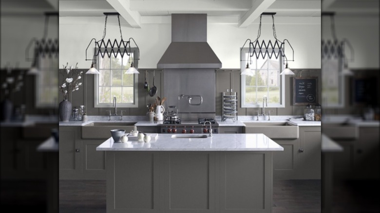 Espectacular cocina de color gris oscuro con originales lámparas negras y ventanas a ambos lados de la estufa.