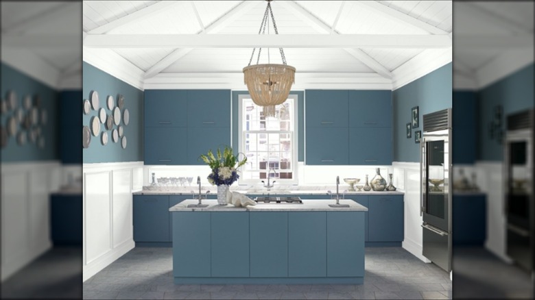 Cocina clásica pintada de azul con una lámpara colgante y techos de carpintería blanca.
