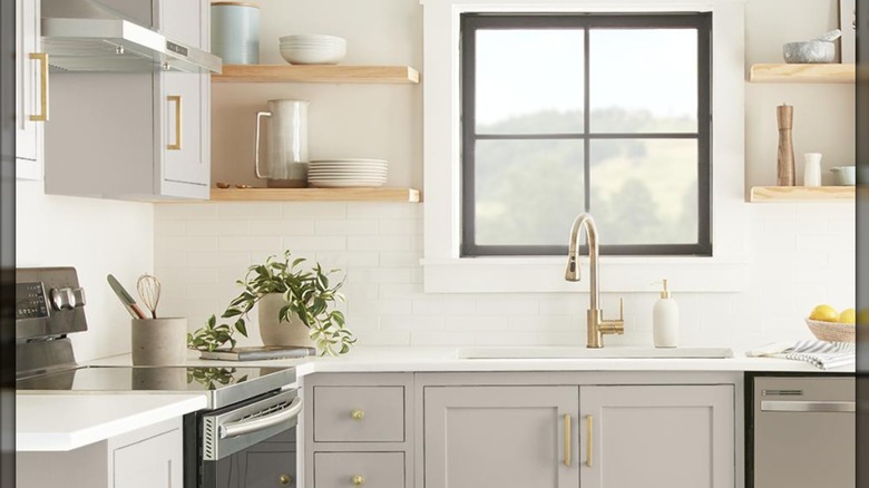Diseño de cocina moderna en gris topo con estantes abiertos y pomos de latón.