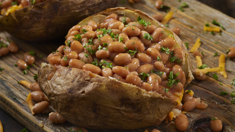 Patata al horno con frijoles, queso y guarnición de perejil picado