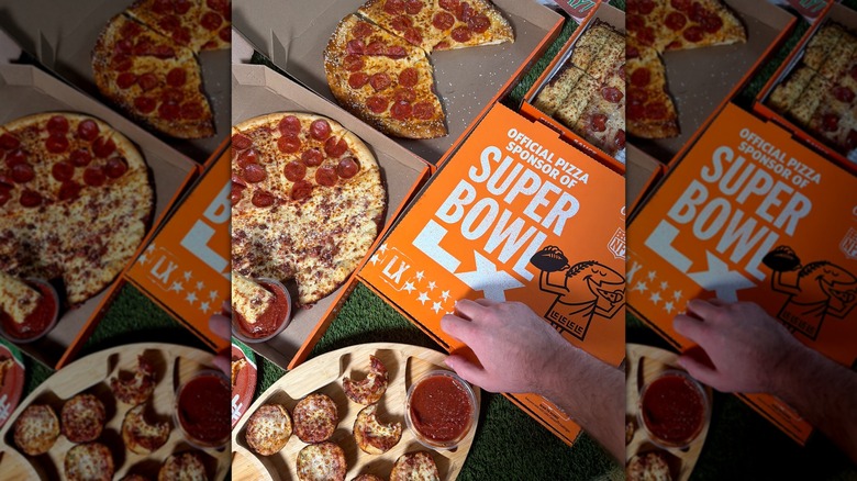 Una mano abriendo una caja de Little Caesars, junto a tres cajas de pizza ya abiertas