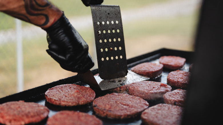 Voltear hamburguesas en una plancha plana