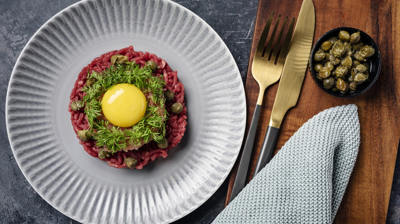 Vista aérea del Steak Tartar cubierto con un huevo crudo.