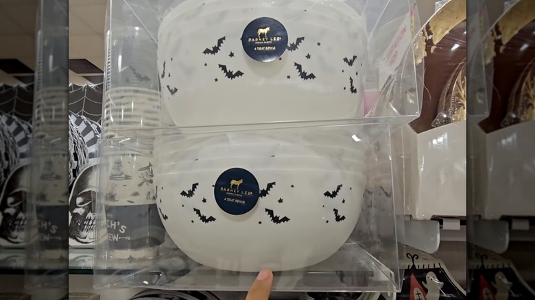 Una mano apuntando a dos juegos de cuatro tazones de plástico blanco con diseños de murciélagos.