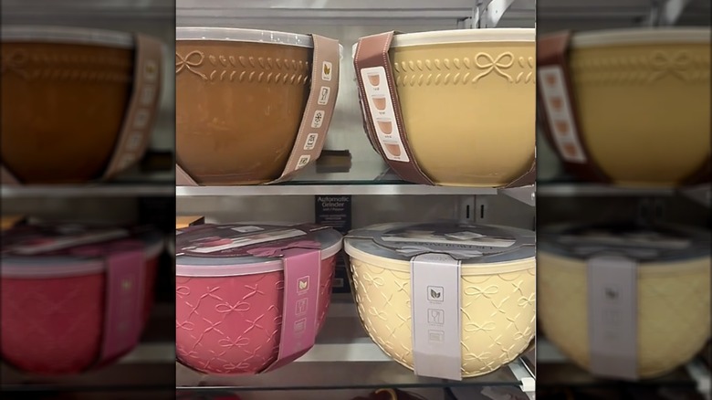 Cuatro colores diferentes de juegos de tazones con un lazo decorativo en un estante de HomeGoods