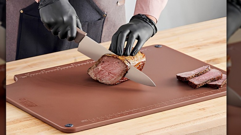 hombre cortando carne cocida en una tabla de cortar marrón