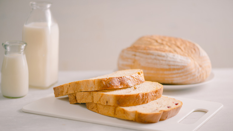 pan sobre una tabla de cortar blanca con lácteos cerca