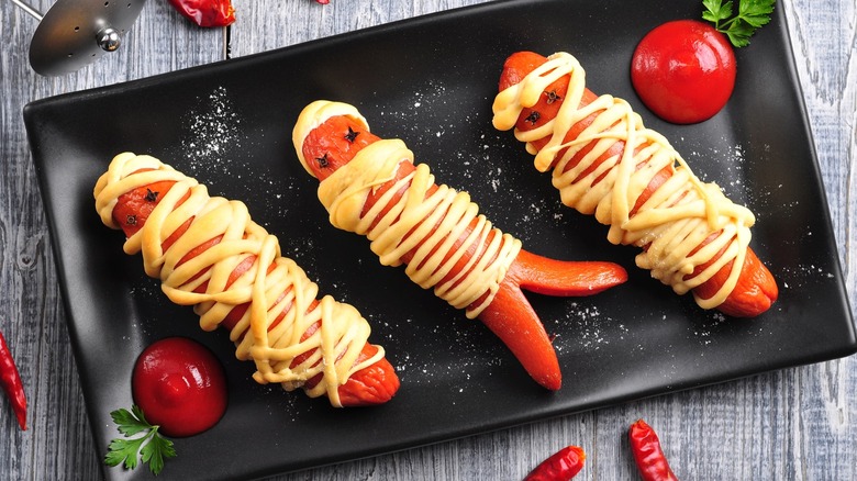 Perritos calientes de momia en un plato negro