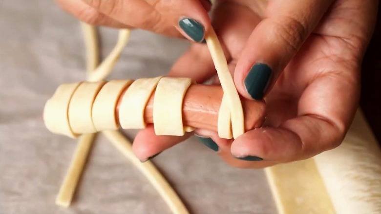 Primer plano de envolver masa de rollo de media luna alrededor de un hot dog
