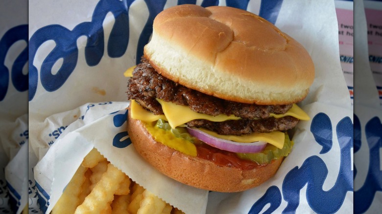 Una ButterBurger de Culver's en papel con la marca Culver's, junto a una bolsa de papas fritas