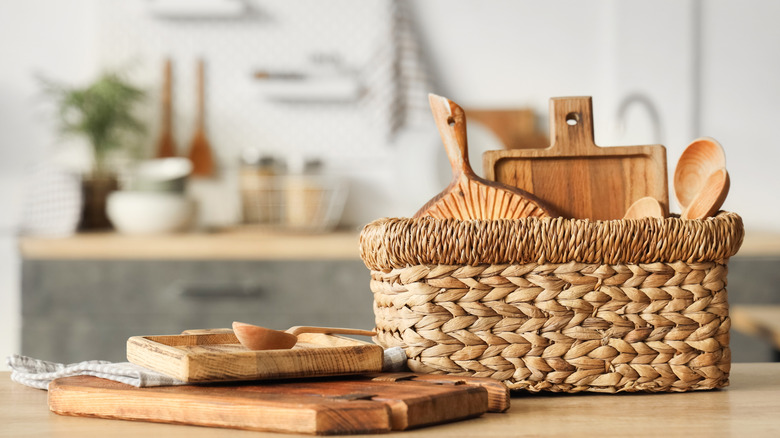 Tablas de cortar y cucharas de madera en una cesta en la cocina.
