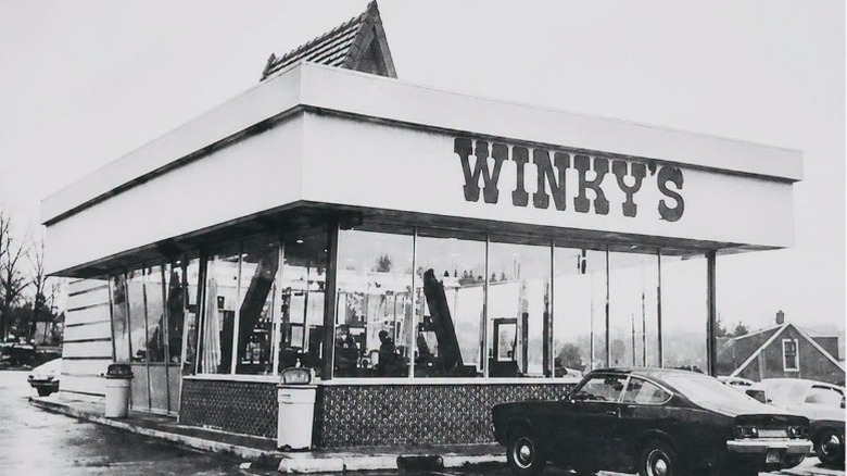 Fotografía en blanco y negro del escaparate de Winky con un automóvil estacionado enfrente