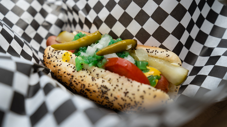 Hot dog estilo Chicago sobre un papel cuadriculado dentro de una bandeja para servir