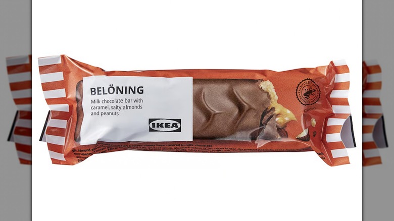 Una barra de chocolate con leche Belöning con caramelo, almendras y maní sobre un fondo blanco.