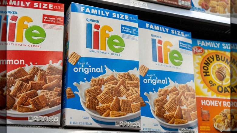 Dos cajas de cereales Life originales en el estante de una tienda, entre cajas de otro sabor de cereales Life y manojos de avena con miel