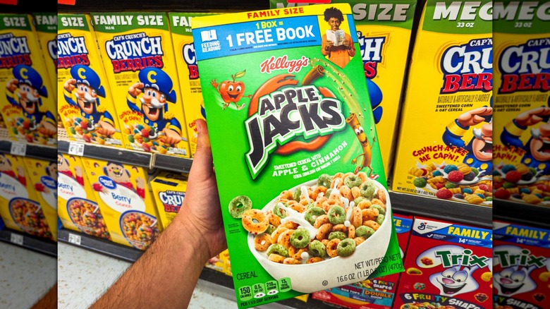 Una mano sosteniendo una caja de cereal Apple Jacks