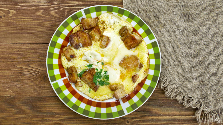 plato a cuadros verdes sobre madera y arpillera, con huevos y ostras encima