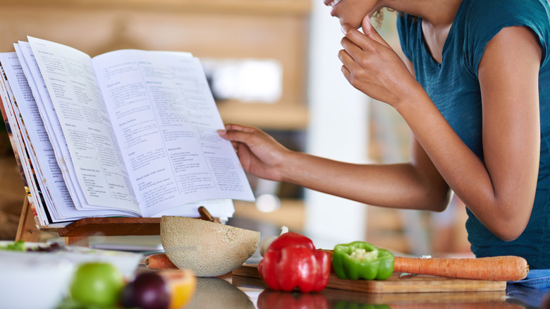 mujer mirando un libro de cocina sobre un soporte