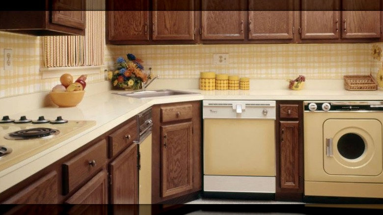 Una cocina con papel tapiz amarillo y electrodomésticos Harvest Gold.