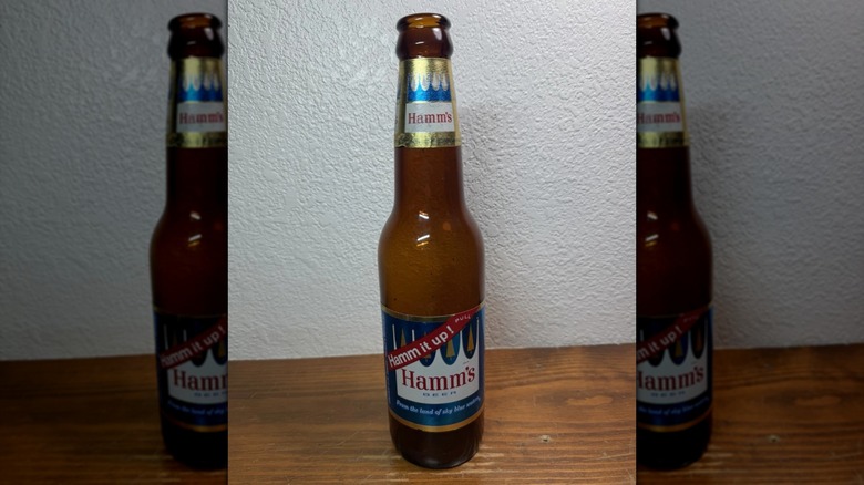 Una botella de Hamm sobre una superficie de madera contra una pared blanca