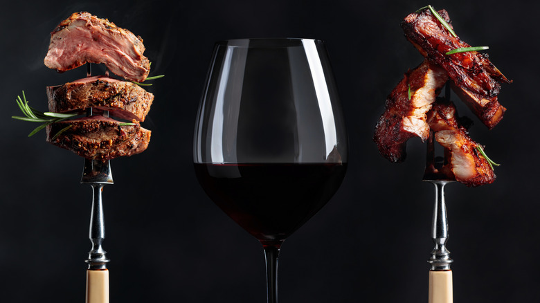 Dos brochetas de carne cocida enmarcando una copa de vino tinto