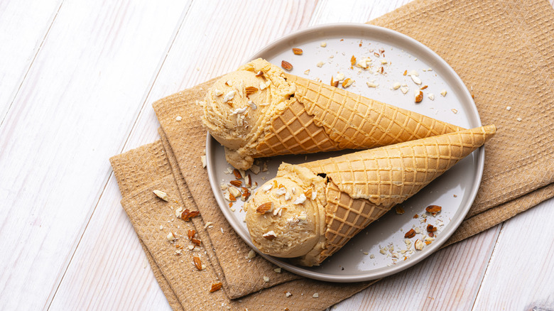 Dos conos de helado en un plato espolvoreados con almendras picadas