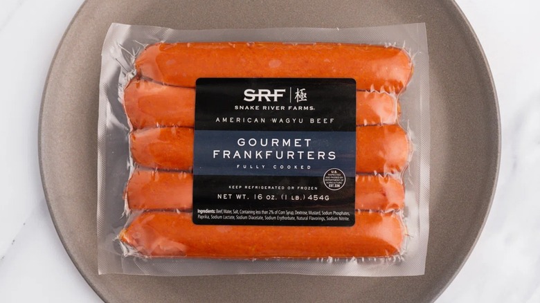 Snake River Farms American Wagyu Gourmet Frankfurters en su paquete sentado en un plato.