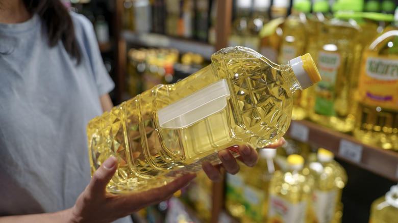 Comprador sosteniendo una botella grande de aceite de cocina