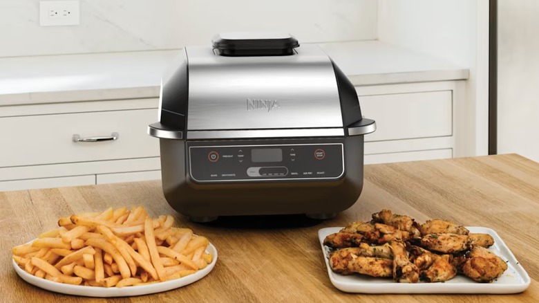 Ninja Foodi Indoor Grill y Air Fryer con un plato de papas fritas y pollo