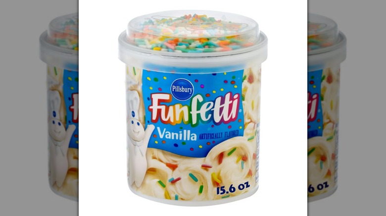 Una tina de Pillsbury Funfetti Vanilla Frosting sobre un fondo blanco.